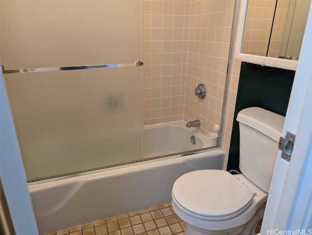 bathroom featuring toilet, tile patterned floors, and bath / shower combo with glass door