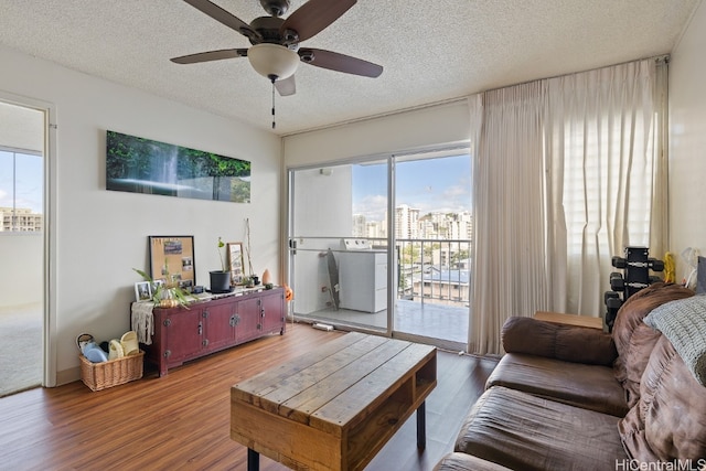 living room with washer / dryer, a textured ceiling, wood-type flooring, and ceiling fan