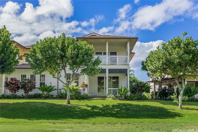 view of front of house featuring a balcony and a front lawn