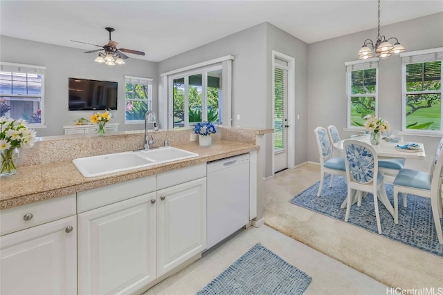 kitchen featuring sink, white dishwasher, pendant lighting, light colored carpet, and white cabinets