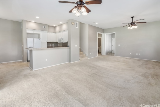 unfurnished living room with light carpet, sink, and ceiling fan