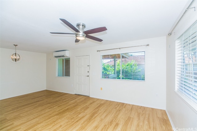 spare room featuring light hardwood / wood-style floors, an AC wall unit, and ceiling fan