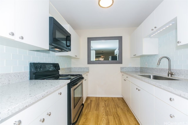 kitchen with light stone countertops, sink, stainless steel range with electric stovetop, white cabinetry, and light hardwood / wood-style floors