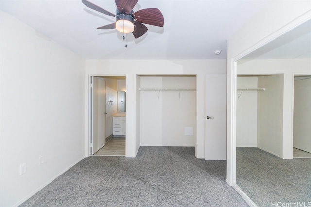 unfurnished bedroom featuring ensuite bathroom, multiple closets, light colored carpet, and ceiling fan