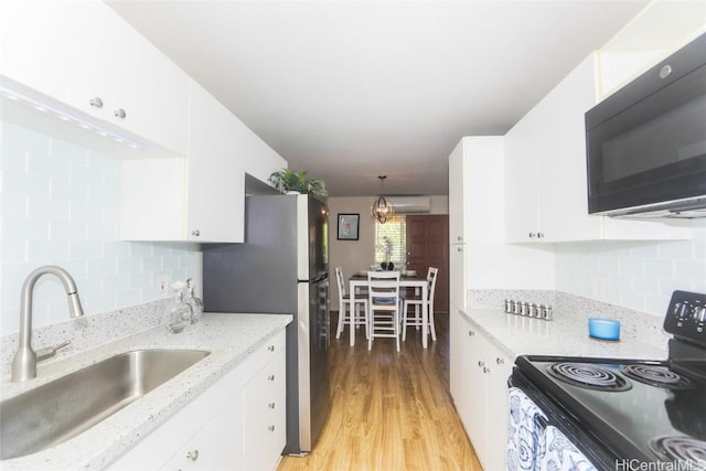 kitchen with black appliances, a sink, white cabinetry, and decorative light fixtures