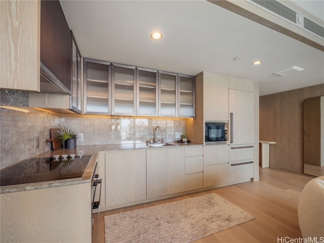 kitchen with decorative backsplash, stainless steel microwave, light wood-type flooring, wall oven, and sink