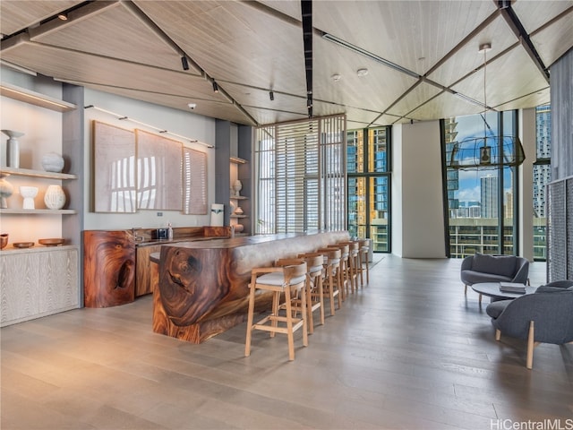 bar featuring a towering ceiling, hardwood / wood-style flooring, and floor to ceiling windows