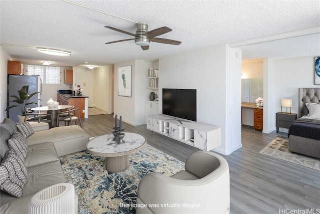 living room with a textured ceiling, hardwood / wood-style flooring, and ceiling fan