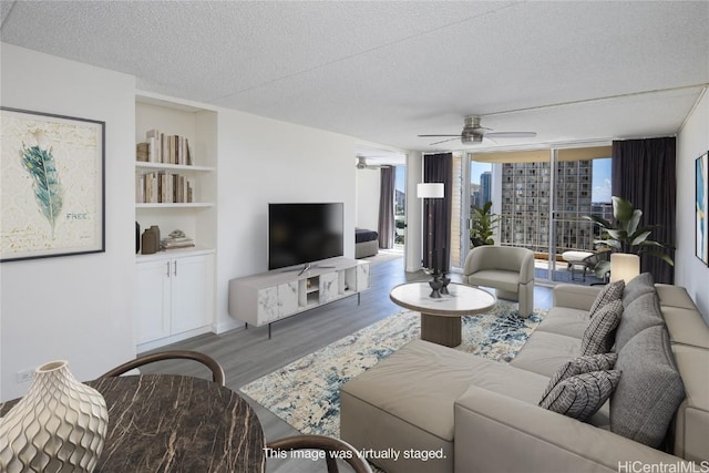 living room with hardwood / wood-style flooring, ceiling fan, a wall of windows, and a textured ceiling