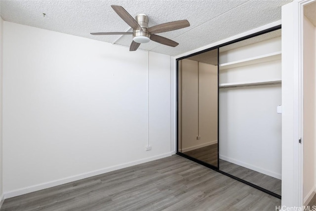 unfurnished bedroom featuring wood-type flooring, a textured ceiling, a closet, and ceiling fan