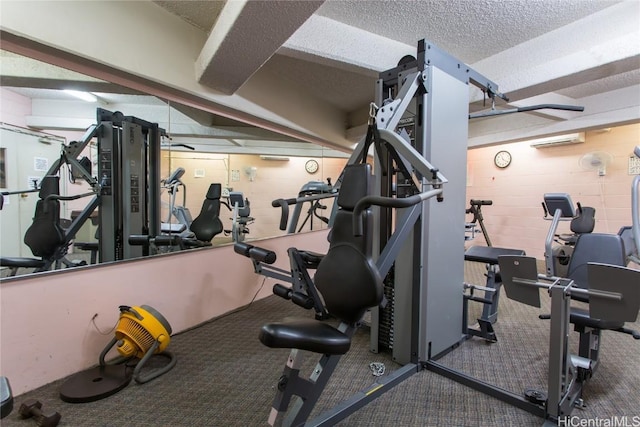 workout area featuring a textured ceiling and a wall unit AC