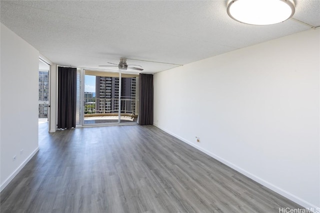 unfurnished room with floor to ceiling windows, dark hardwood / wood-style flooring, and a textured ceiling