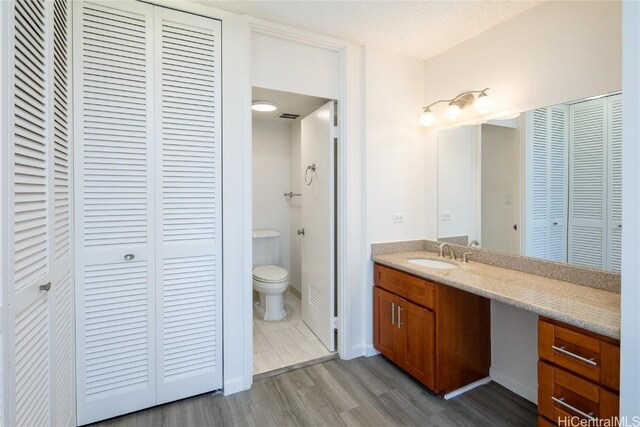 bathroom with vanity, wood-type flooring, a textured ceiling, and toilet