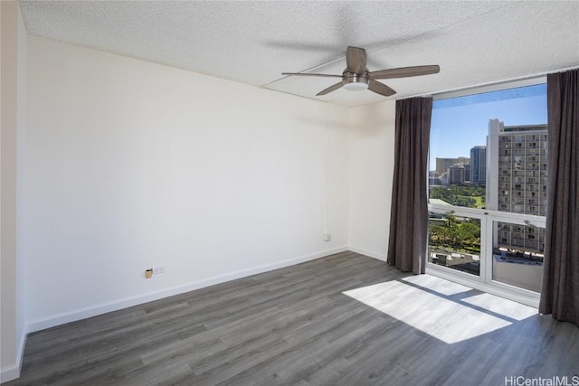 empty room featuring ceiling fan, a healthy amount of sunlight, dark hardwood / wood-style flooring, and a textured ceiling