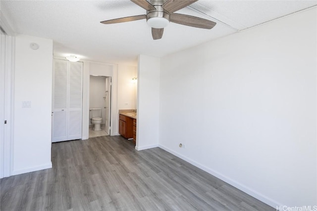 unfurnished bedroom with ceiling fan, light hardwood / wood-style flooring, and ensuite bathroom