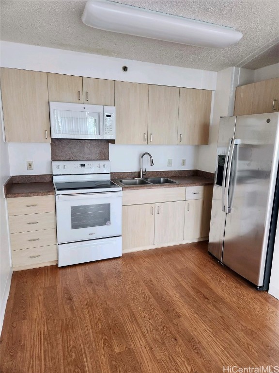 kitchen featuring white appliances, a textured ceiling, sink, and hardwood / wood-style flooring