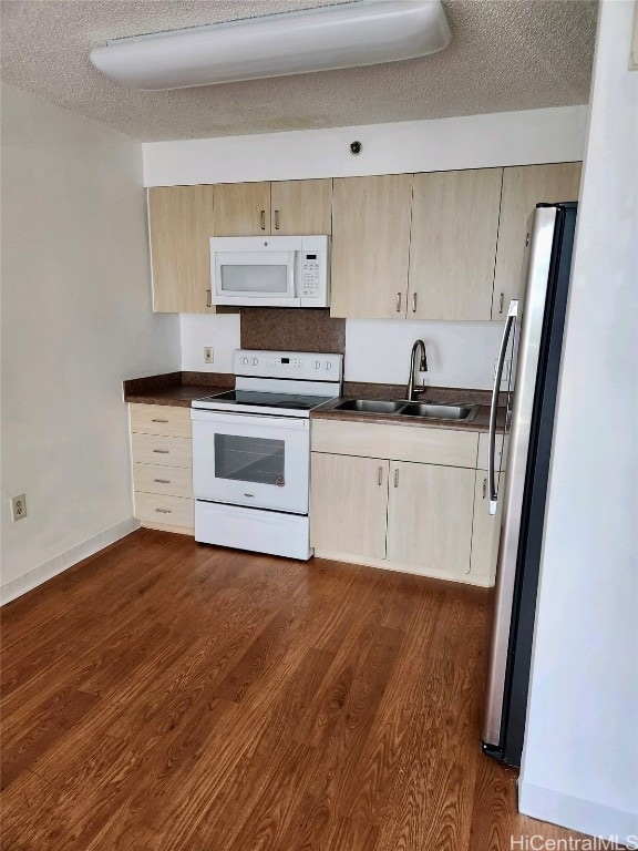 kitchen with dark wood-type flooring, white appliances, a textured ceiling, and sink