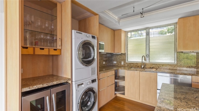 washroom featuring beverage cooler, wood-type flooring, ornamental molding, stacked washer / drying machine, and sink