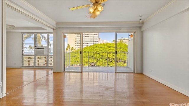 empty room featuring crown molding, cooling unit, light wood-type flooring, and ceiling fan