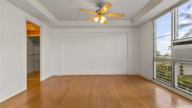 empty room featuring a raised ceiling, ornamental molding, light hardwood / wood-style flooring, and plenty of natural light