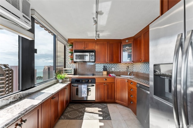 kitchen with stainless steel appliances, sink, light stone countertops, a water view, and tasteful backsplash