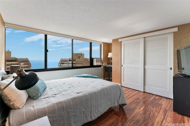 bedroom featuring a water view, wood-type flooring, cooling unit, and floor to ceiling windows