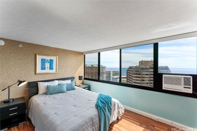 bedroom with hardwood / wood-style floors, multiple windows, and a water view