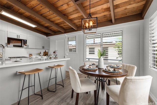 dining room with a chandelier, beam ceiling, wood ceiling, and light hardwood / wood-style flooring