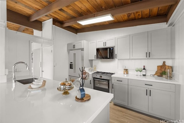 kitchen featuring appliances with stainless steel finishes, sink, vaulted ceiling with beams, and wooden ceiling