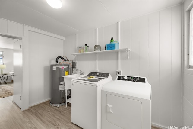 laundry area with separate washer and dryer, water heater, sink, and light hardwood / wood-style flooring