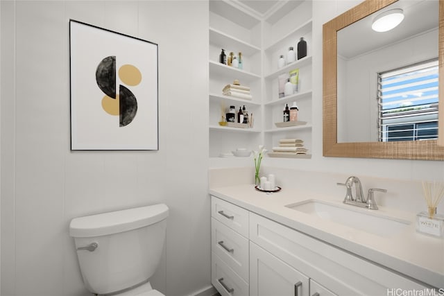 bathroom featuring toilet, vanity, and built in shelves