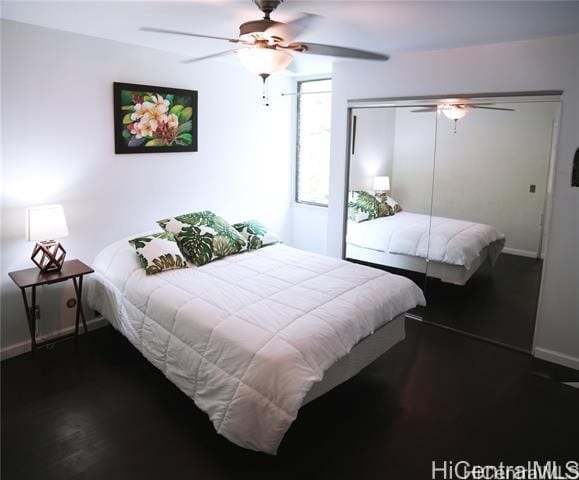 bedroom featuring ceiling fan, dark wood-type flooring, a closet, and baseboards