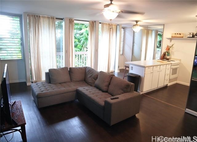 living area featuring dark wood-type flooring, ceiling fan, and baseboards