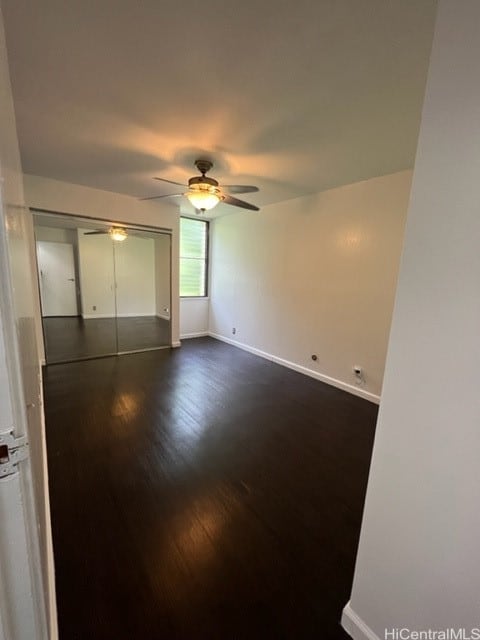 unfurnished bedroom featuring dark wood-type flooring, a closet, and ceiling fan