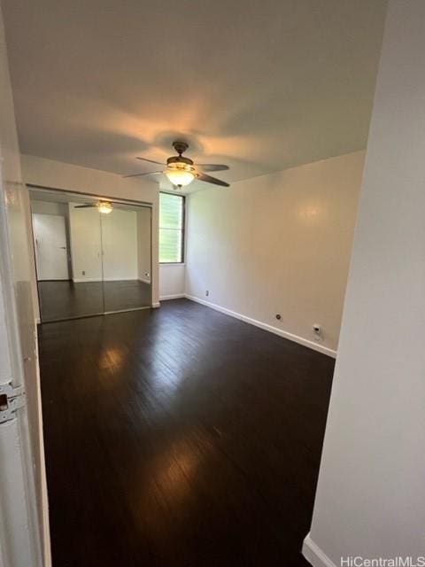 unfurnished bedroom with ceiling fan, dark wood-type flooring, a closet, and baseboards