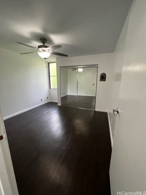 unfurnished bedroom with dark wood-type flooring, a closet, and ceiling fan