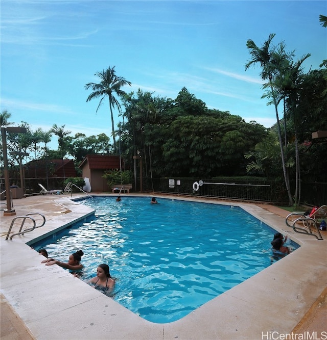 community pool featuring a patio, an outdoor structure, and fence