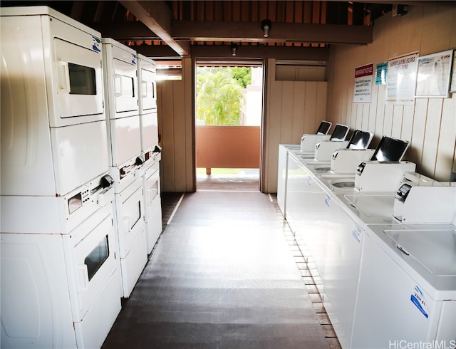 common laundry area featuring stacked washer and dryer, washer and dryer, wood finished floors, and wood walls