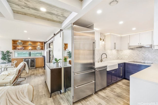 kitchen with stainless steel appliances, a barn door, light countertops, and white cabinetry