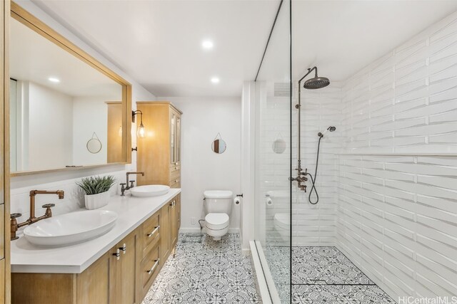 full bathroom with double vanity, a sink, toilet, and a walk in shower