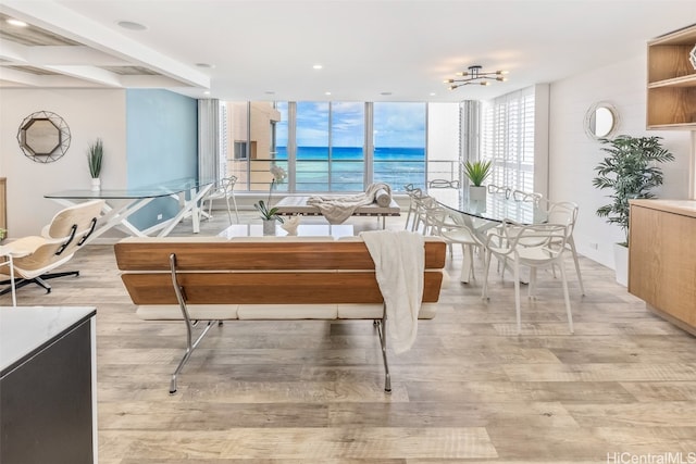 dining space with beamed ceiling, a notable chandelier, light wood-type flooring, expansive windows, and a water view