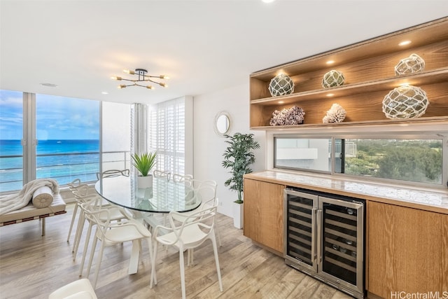 interior space with a water view, light hardwood / wood-style floors, wine cooler, and bar