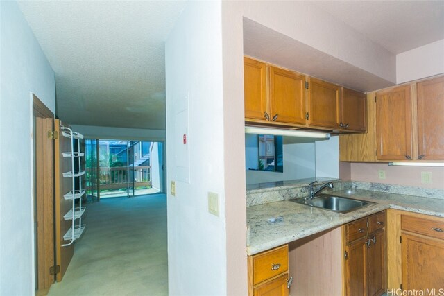 kitchen with light stone counters, a textured ceiling, and sink