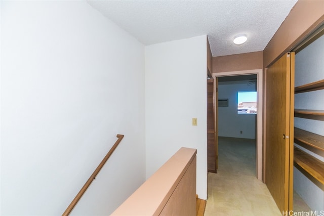 hall featuring light carpet and a textured ceiling