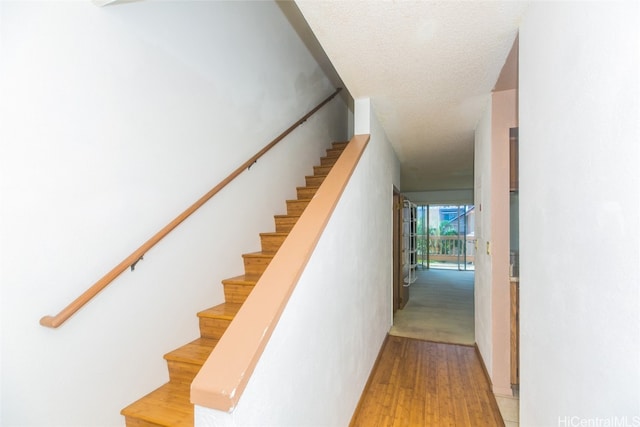 staircase featuring a textured ceiling and hardwood / wood-style flooring