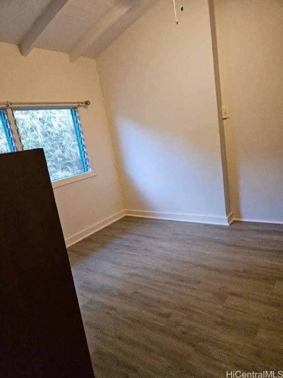 spare room featuring dark hardwood / wood-style flooring and vaulted ceiling with beams