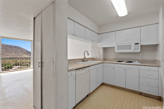 kitchen with white appliances, a mountain view, white cabinetry, and sink