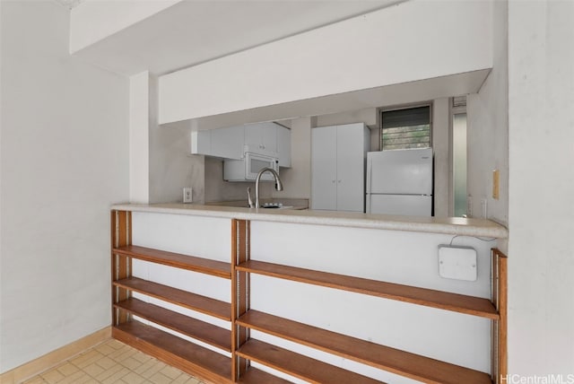 interior space with sink, white cabinetry, and white appliances