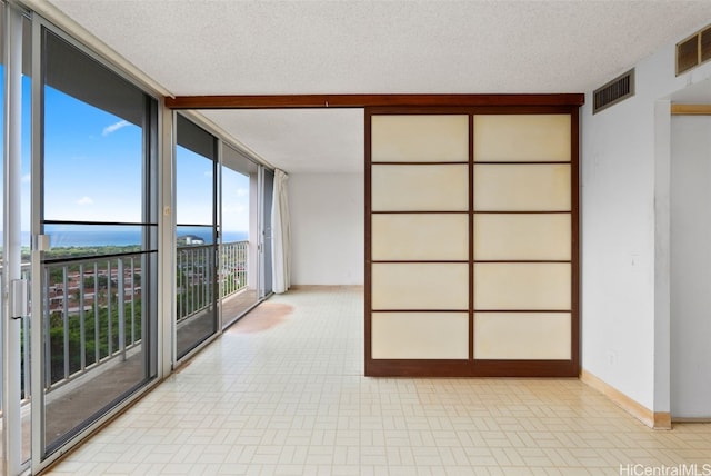 unfurnished room with a textured ceiling and floor to ceiling windows