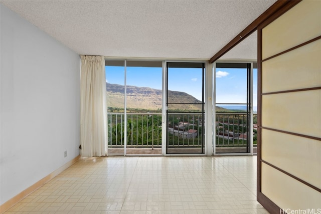 empty room with expansive windows, a mountain view, and a textured ceiling